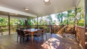 a porch with a wooden table and chairs on a deck at Decked out for a Fantastic Holiday - (Whole house) Winnett St, Woorim in Woorim