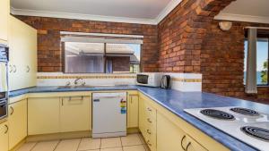 une cuisine avec des armoires jaunes et un mur en briques dans l'établissement Boasting some of Bribie's Best Waterviews, à Bongaree