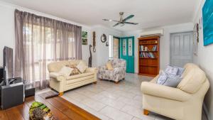 a living room with two chairs and a tv at Delightful Duplex on Rose Ct, Bongaree in Bongaree