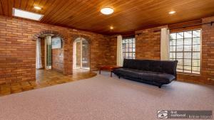 a living room with a black couch in a brick wall at Banksia Gem One Street Back From Waterfront in Banksia Beach
