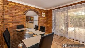 a dining room with tables and chairs and a brick wall at Banksia Gem One Street Back From Waterfront in Banksia Beach