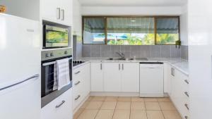 a kitchen with white cabinets and a sink and a window at Spectacular Waterviews and Sunsets in Bongaree