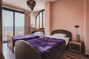 een hotelkamer met 2 bedden en een balkon bij Auberge RIAD DLIM Tamraght in Tamraght Ouzdar