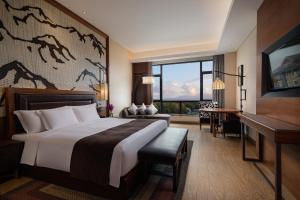 ein Hotelzimmer mit einem großen Bett und einem Schreibtisch in der Unterkunft Crowne Plaza Resort Changbaishan Hot Spring, an IHG Hotel in Antu