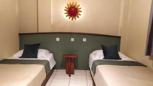a room with two beds and a mirror on the wall at Hotel La Hasienda in Kupang