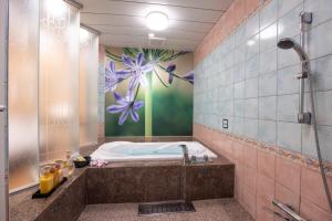 uma casa de banho com uma banheira e uma parede de flores em VALENTINE RESORT(大人専用） em Kasama