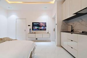 ein weißes Schlafzimmer mit einem Bett und einem TV an der Wand in der Unterkunft Luxury Studio apartments Chevron lekki in Lekki