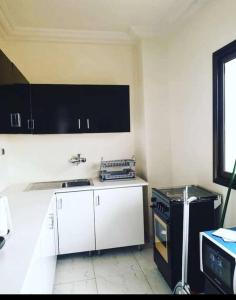 cocina con armarios blancos y estufa negra en Appartement luxueux ouaga2000(2 chambres ), en Ouagadougou