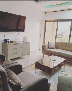Il comprend un salon avec des canapés et une télévision à écran plat. dans l'établissement Appartement luxueux ouaga2000(2 chambres ), à Ouagadougou