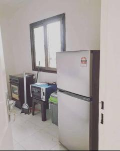 Il comprend une cuisine équipée d'un réfrigérateur blanc et d'une cuisinière. dans l'établissement Appartement luxueux ouaga2000(2 chambres ), à Ouagadougou