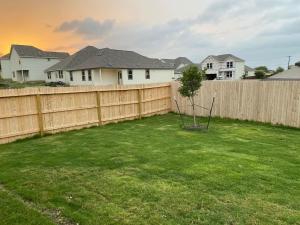 a backyard with a fence and a tree in the grass at New home less than 5 minutes from Lackland Base private room in San Antonio