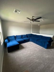 Sofá azul en la sala de estar con ventilador de techo en New home less than 5 minutes from Lackland Base private room, en San Antonio