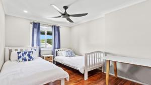 a bedroom with two cribs and a ceiling fan at 1 Ilya Street Currimundi QLD in Kawana Waters +16 photos