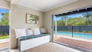 a room with a couch and a balcony with a pool at 1 Ilya Street Currimundi QLD in Kawana Waters