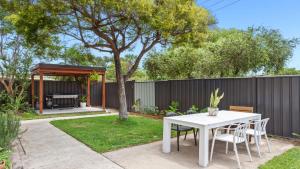 a white table and chairs in a backyard with a fence at 1 Ilya Street Currimundi QLD in Kawana Waters