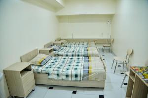 two beds in a room with chairs and a desk at YUKSALISH HOSTEL in Samarkand