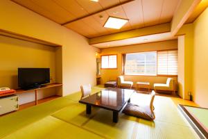 鹿角的住宿－龜之井酒店 秋田湯瀨，客厅配有桌子和电视