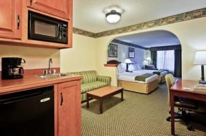 Habitación de hotel con cama y sala de estar. en Holiday Inn Express Hotel & Suites Forest, an IHG Hotel, en Forest