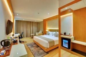 a hotel room with a bed and a television at Clarion Hotel Bangalore in Bangalore
