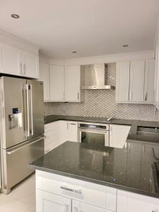 a kitchen with white cabinets and stainless steel appliances at 4 Bedrooms Beautiful Townhouse in Montréal