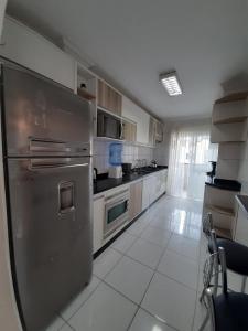 una cocina con nevera de acero inoxidable y armarios en Estrela do mar 3 dormt, en Bombinhas
