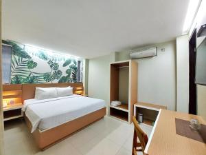 a bedroom with a bed and a desk and a table at Shinta Guesthouse in Malang