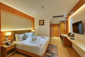 a hotel room with a bed and a television at Clarion Hotel Bangalore in Bangalore