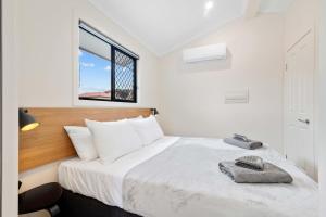 a bedroom with a bed with white sheets and a window at Kenilworth Country Cabins in Kenilworth