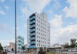 a tall white building with blue windows on a street at Miyako Daiichi Hotel in Miyako-jima