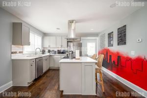a kitchen with white cabinets and a red painting on the wall at Luxury Sports Art Gallery - 15 mins to ATL Battery in Marietta