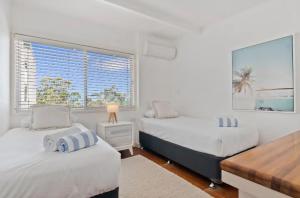 Dieses weiße Zimmer verfügt über 2 Betten und ein Fenster. in der Unterkunft Ocean Views Central to everything , 2 bed, 2 minute walk to Beach in Noosa Heads