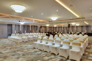 Clarion Hotel Bangalore في بانغالور: غرفه كبيره فيها كراسي بيضاء وناس فيها