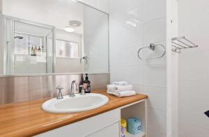 ein weißes Badezimmer mit einem Waschbecken und einem Spiegel in der Unterkunft Ocean Views Central to everything , 2 bed, 2 minute walk to Beach in Noosa Heads