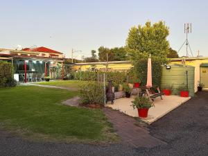 un patio con bancos y plantas en un patio en Nanango Antler Motel, en Nanango