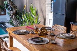 a wooden table with plates and glasses on it at [Seminyak central] private 3 bedrooms villa with swimming pool in Seminyak