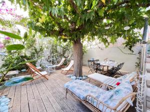 eine Terrasse mit einem Baum, Stühlen und einem Tisch in der Unterkunft Les galets bleus de Calvi in Calvi