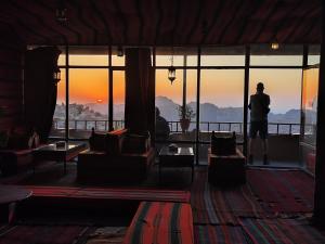 un hombre de pie en una habitación mirando a la puesta de sol en Rocky Mountain Hotel, en Wadi Musa