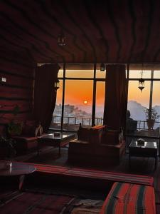 a living room with couches and a view of the sunset at Rocky Mountain Hotel in Wadi Musa