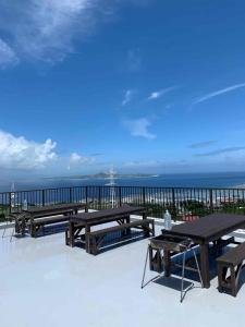 a patio with picnic tables and the ocean in the background at Yukurina Resort Okinawa in Motobu