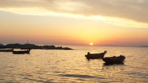 パトラにあるPatras White Castleの三隻の船が夕日に水中に座っている