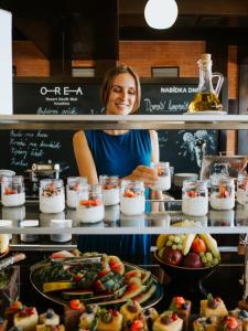 a woman standing behind a counter with food at OREA Resort Devět Skal Vysočina in Sněžné