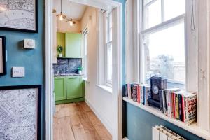 einen Flur mit einem Regal mit Büchern und einem Fenster in der Unterkunft Sunny Corner Apartment in Center of London in London