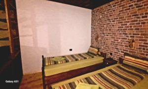 a room with two beds in a brick wall at Семеен хотел-ресторант Маламовата къща in Gotse Delchev