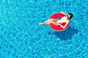 a woman sitting on a red circle in a swimming pool at BelAire Bangkok Sukhumvit - SHA Extra Plus in Bangkok