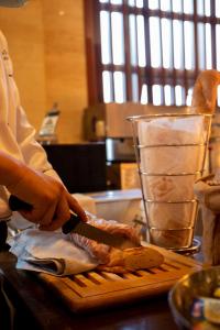 uma pessoa a cortar carne numa tábua de cortar com uma faca em Holiday Inn Qingdao Expo, an IHG Hotel em Qingdao