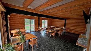 restauracja z drewnianymi ścianami, stołami i krzesłami w obiekcie penzion a kemp Harasov w mieście Vysoká