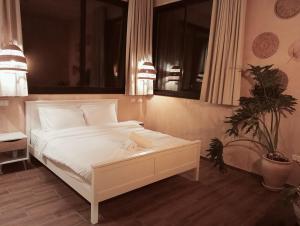 Un dormitorio con una cama blanca y una planta en שיח מדבר לינה בנגב Burning Bush Negev, en Merhav Am