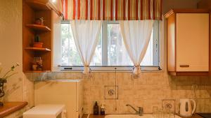 a bathroom with a sink and a window with curtains at Artemis Apartment,Beach two-bedroom in Artemida