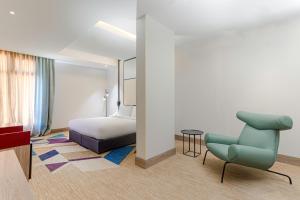 a hotel room with a bed and a blue chair at Ewaa Express Hotel - Al Jouf in Sakakah