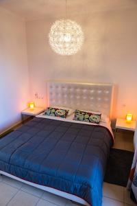 sypialnia z dużym niebieskim łóżkiem i żyrandolem w obiekcie Villa Pandora - Angela & Michali w mieście Maleme